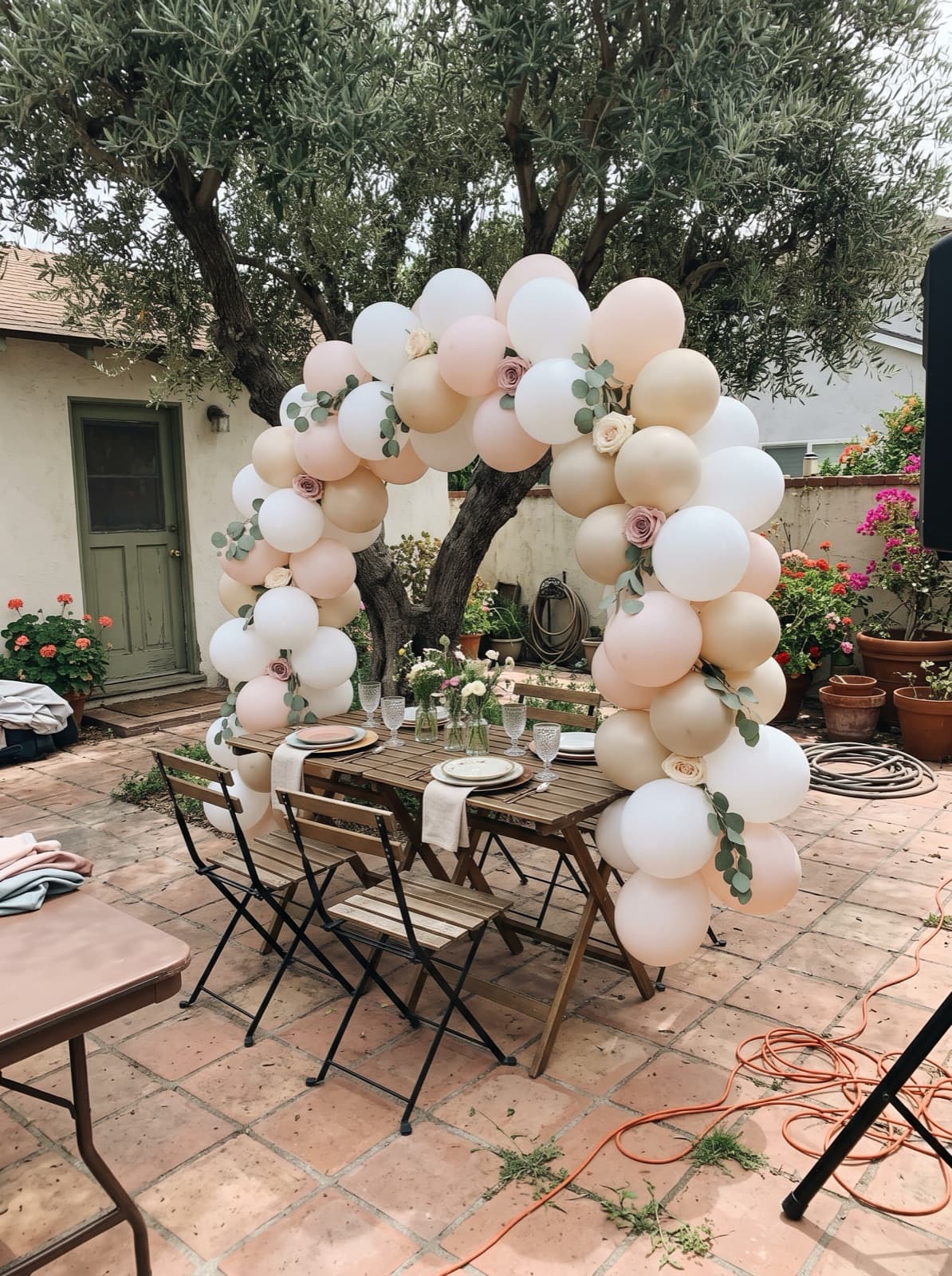 Blush and champagne arch with roses and eucalyptus on a shaded patio