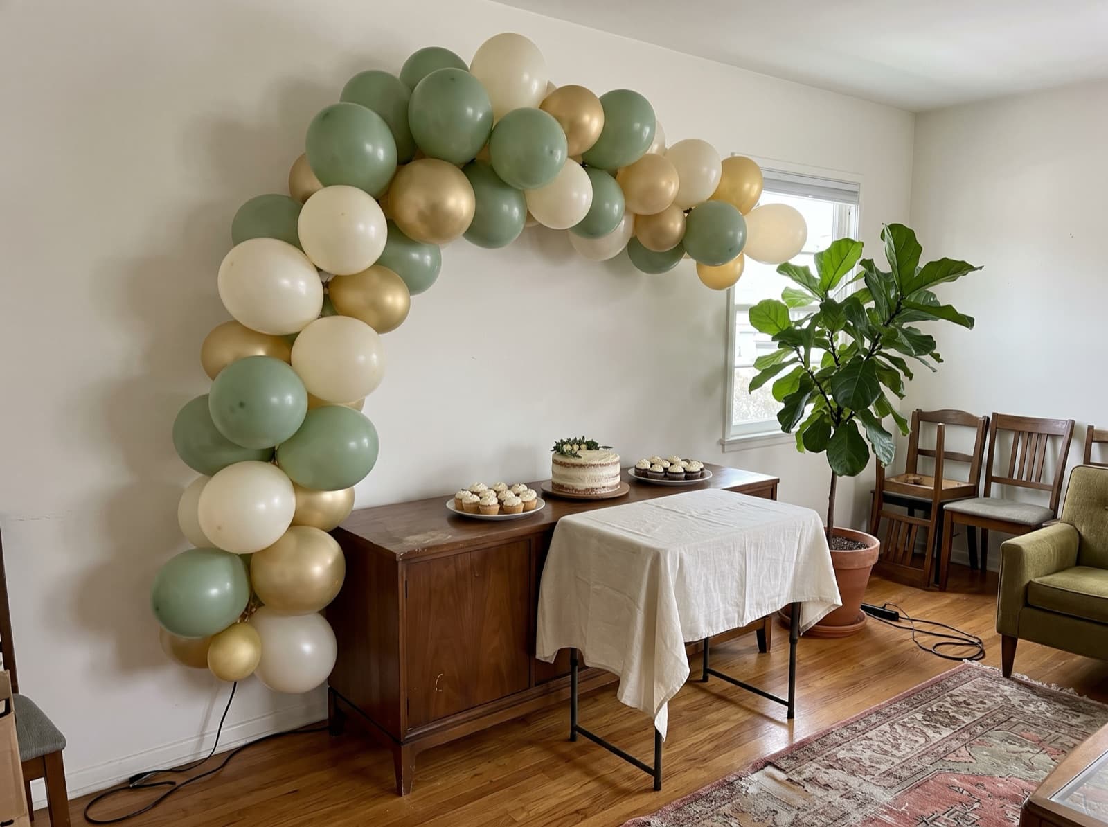 Sage, ivory and soft gold organic arch above a dessert spread