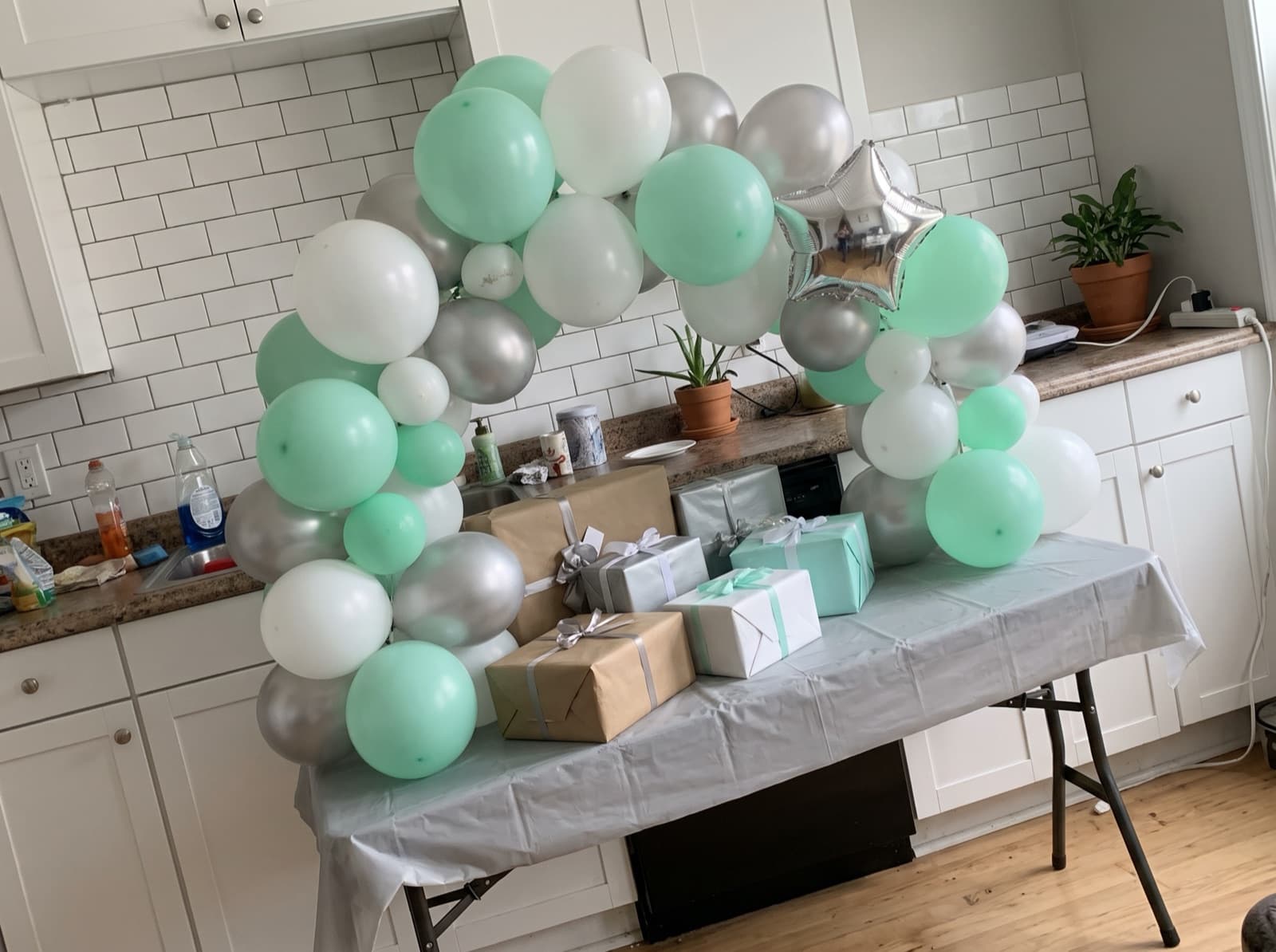 Mint, white and silver tabletop arch behind wrapped gifts